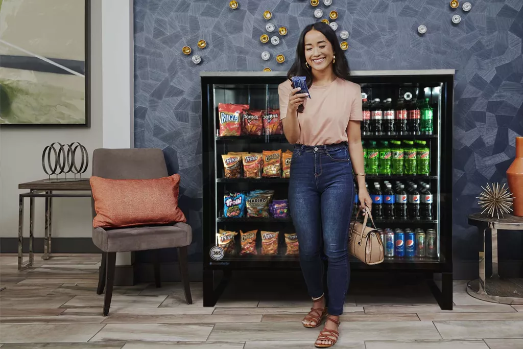 Resident grabbing a snack from a smart market in a lobby lounge